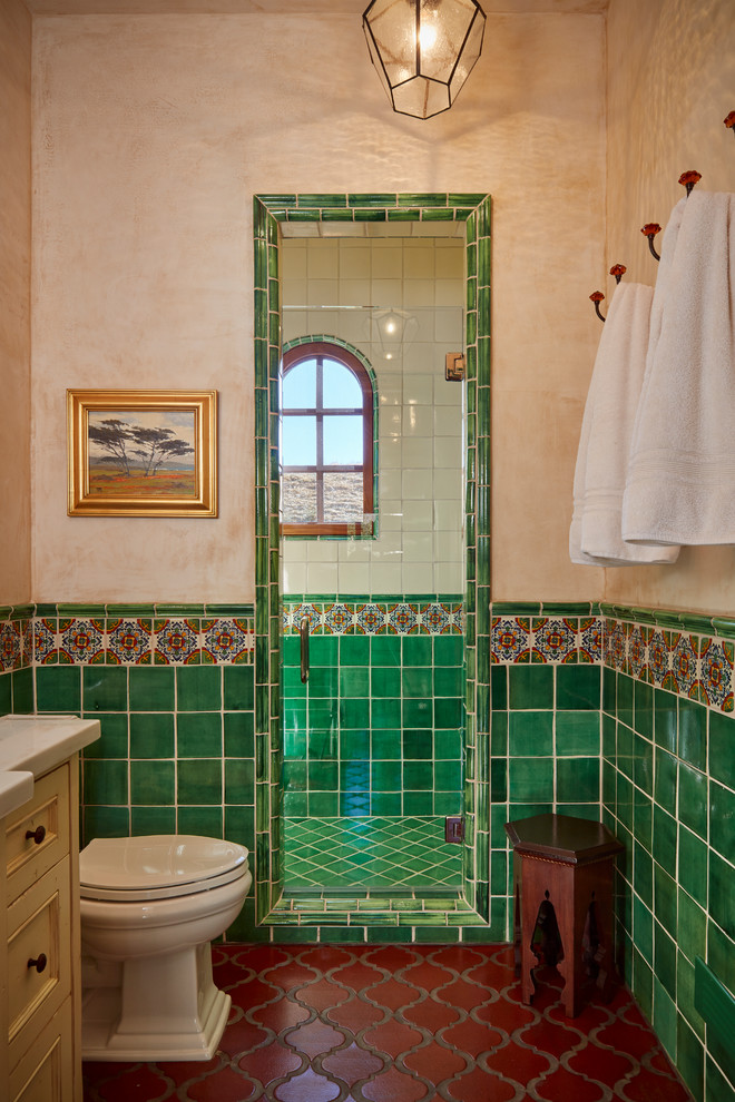 This is an example of a mediterranean 3/4 bathroom in Other with recessed-panel cabinets, beige cabinets, an alcove shower, green tile, multi-coloured tile, beige walls, red floor and a hinged shower door.