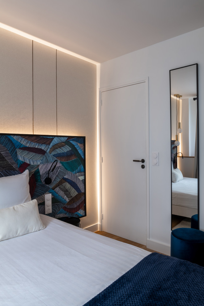 Ispirazione per una grande camera degli ospiti minimal con pareti blu, parquet chiaro, pavimento marrone e boiserie