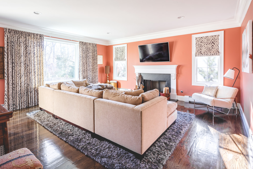 Photo of a mid-sized traditional enclosed family room in New York with orange walls, dark hardwood floors, a standard fireplace, a concrete fireplace surround, a wall-mounted tv and brown floor.