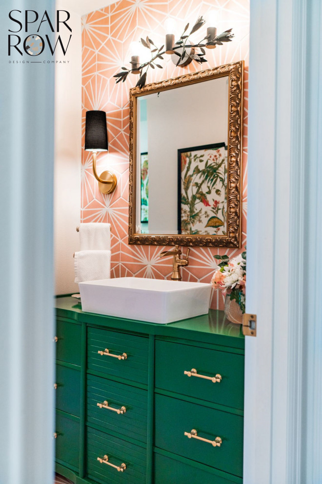 This is an example of a small eclectic family bathroom with beaded cabinets, green cabinets, an alcove bath, an alcove shower, a two-piece toilet, pink tiles, ceramic tiles, white walls, ceramic flooring, a vessel sink, wooden worktops, pink floors, a sliding door, green worktops, a single sink and a freestanding vanity unit.
