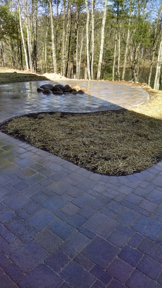 Photo of a rustic partial sun backyard concrete paver landscaping with a fire pit for summer.