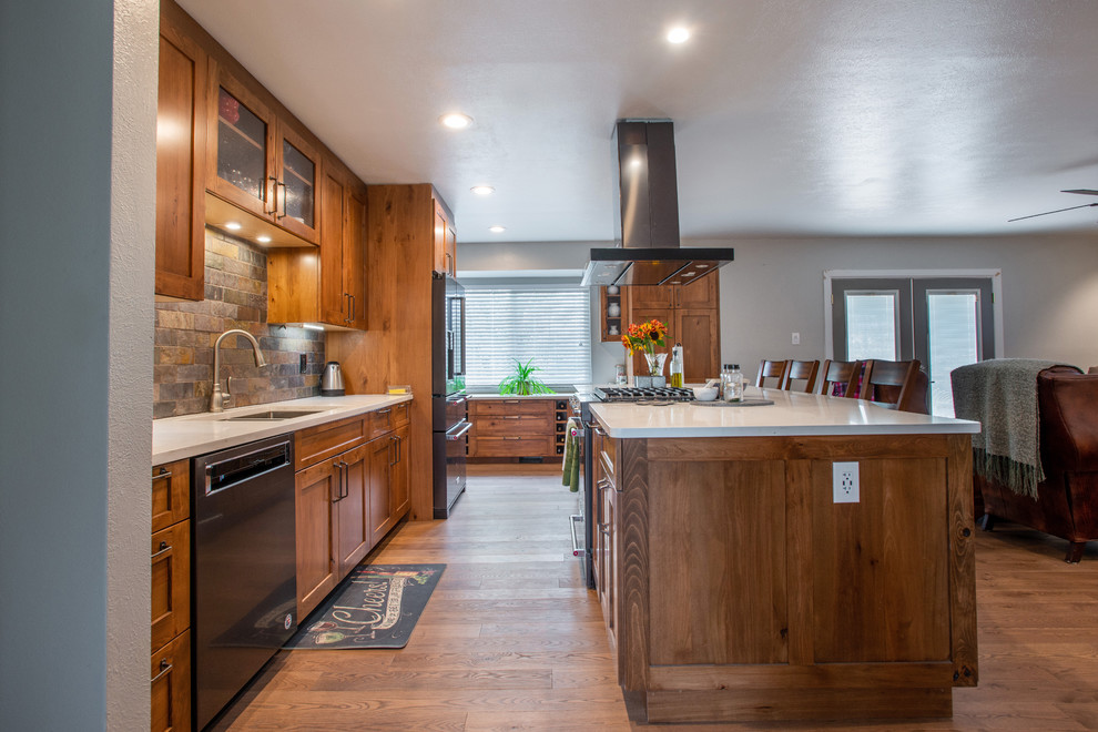 This is an example of a large country l-shaped eat-in kitchen in Other with an undermount sink, shaker cabinets, brown cabinets, quartz benchtops, multi-coloured splashback, slate splashback, stainless steel appliances, medium hardwood floors, with island, brown floor and white benchtop.