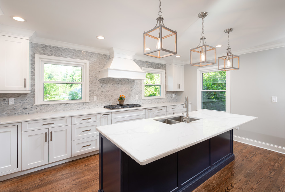Inspiration for a large transitional l-shaped medium tone wood floor and brown floor eat-in kitchen remodel with a double-bowl sink, shaker cabinets, white cabinets, quartz countertops, gray backsplash, mosaic tile backsplash, stainless steel appliances, an island and white countertops