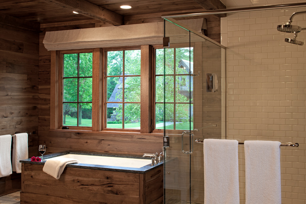 Photo of a country master bathroom in Minneapolis with medium wood cabinets, soapstone benchtops, a drop-in tub, a curbless shower, white tile, subway tile, brown walls and slate floors.