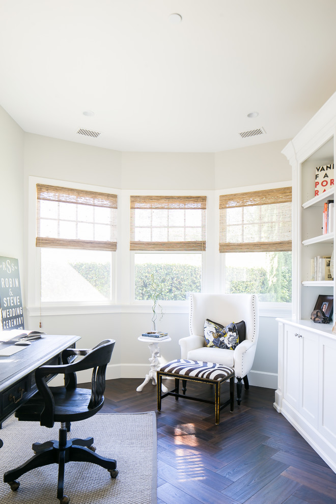 This is an example of a beach style study room in Orange County with beige walls, dark hardwood floors, a freestanding desk and brown floor.