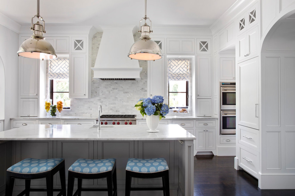 Example of a classic dark wood floor and brown floor kitchen design in Atlanta with a single-bowl sink, recessed-panel cabinets, white cabinets, white backsplash, stainless steel appliances and an island