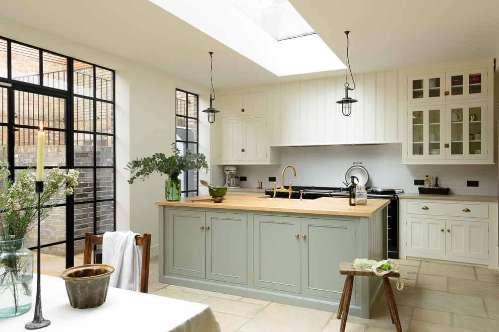 This is an example of a large traditional open plan kitchen in Other with a farmhouse sink, beaded inset cabinets, white cabinets, wood benchtops, white splashback, subway tile splashback, black appliances and with island.