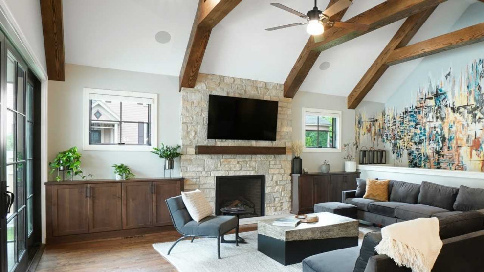 Exemple d'un salon tendance ouvert avec un mur multicolore, un sol en bois brun, un manteau de cheminée en pierre, un téléviseur fixé au mur, un sol marron et poutres apparentes.