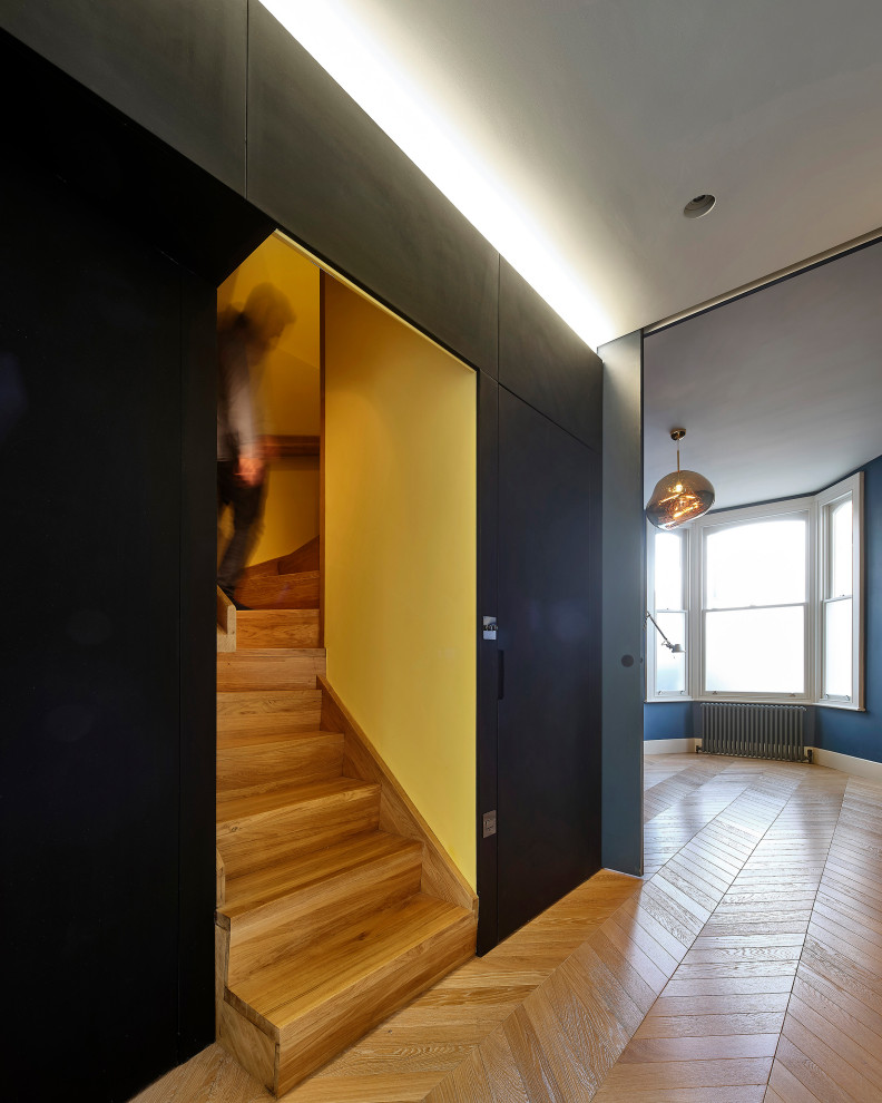 Mid-sized contemporary wood u-shaped staircase in London with wood risers, wood railing and wood walls.