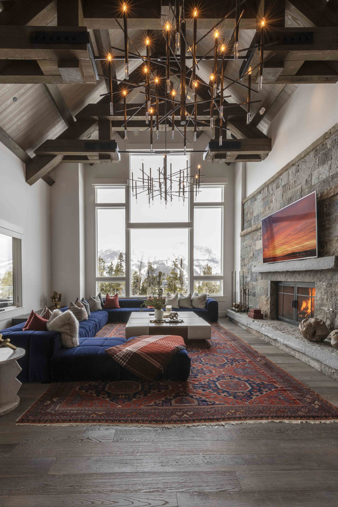 This is an example of a country open concept living room in Other with white walls, dark hardwood floors, a standard fireplace, a stone fireplace surround, a wall-mounted tv and brown floor.