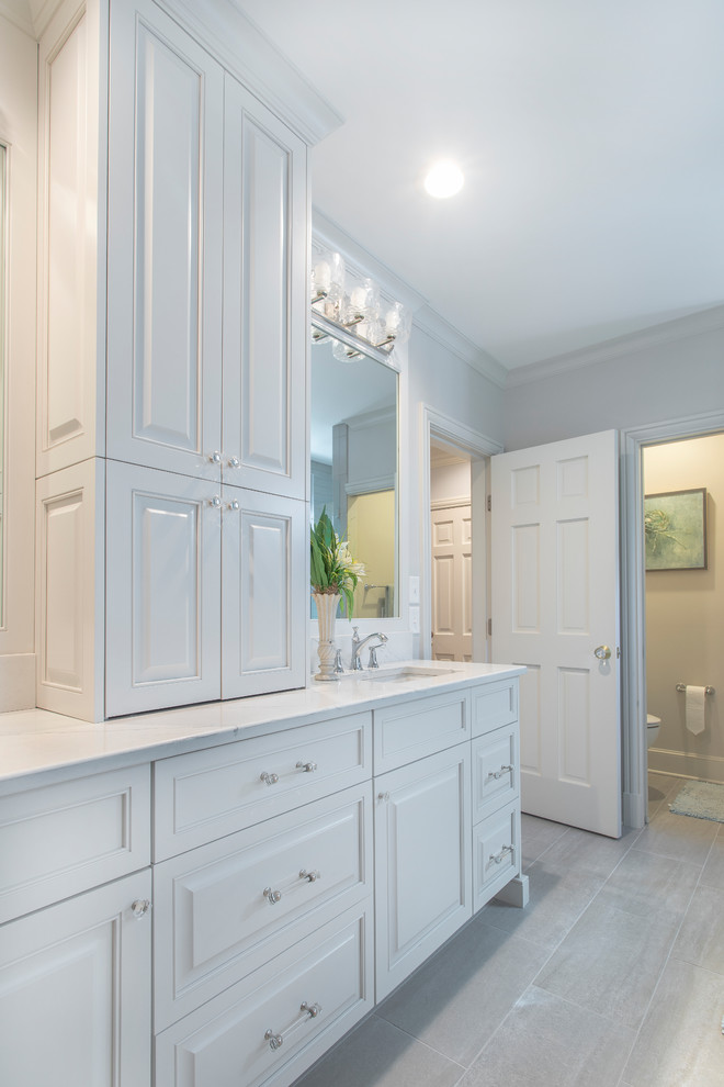 Large traditional master bathroom in Charlotte with raised-panel cabinets, white cabinets, a freestanding tub, white tile, subway tile, white walls, porcelain floors, an undermount sink, engineered quartz benchtops, grey floor and white benchtops.