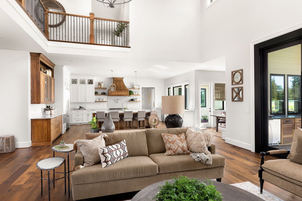 Expansive country open concept living room in Portland with white walls, medium hardwood floors, a standard fireplace, a stone fireplace surround and a wall-mounted tv.