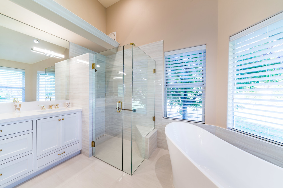 This is an example of a mid-sized modern master bathroom in Other with shaker cabinets, white cabinets, a freestanding tub, a curbless shower, a one-piece toilet, beige tile, porcelain tile, beige walls, porcelain floors, an undermount sink, engineered quartz benchtops, white floor, a hinged shower door and white benchtops.