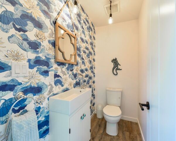 Inspiration for a small beach style powder room in Calgary with beaded inset cabinets, white cabinets, a one-piece toilet, white tile, ceramic tile, white walls, vinyl floors, engineered quartz benchtops and grey floor.