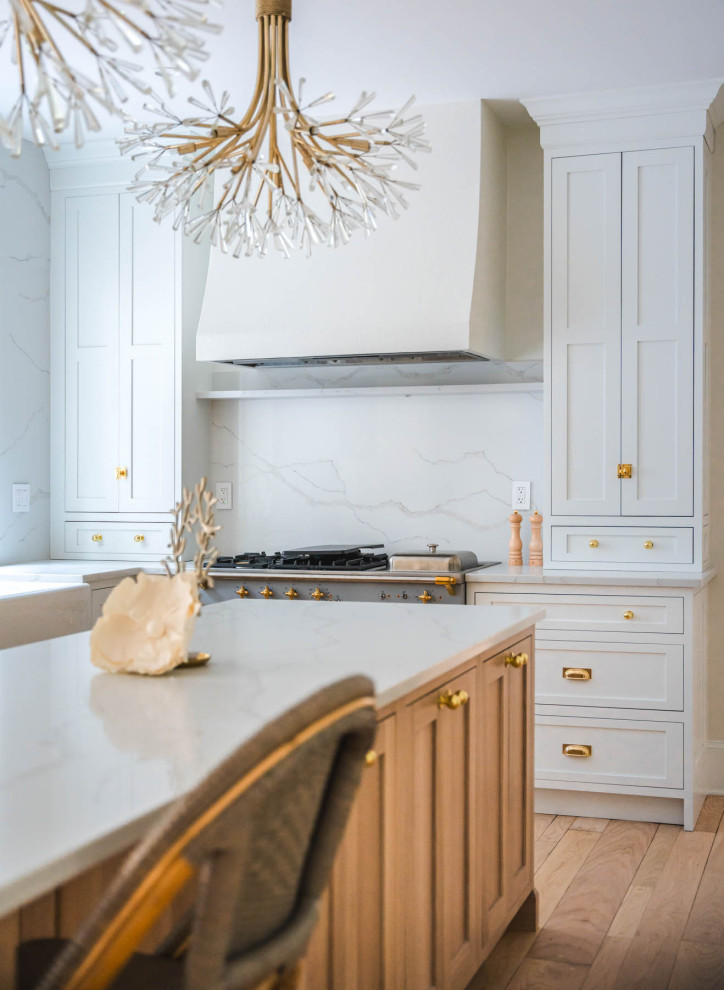 This is an example of a mid-sized u-shaped separate kitchen in DC Metro with a farmhouse sink, shaker cabinets, white cabinets, quartz benchtops, white splashback, engineered quartz splashback, white appliances, light hardwood floors, with island, beige floor, white benchtop and exposed beam.