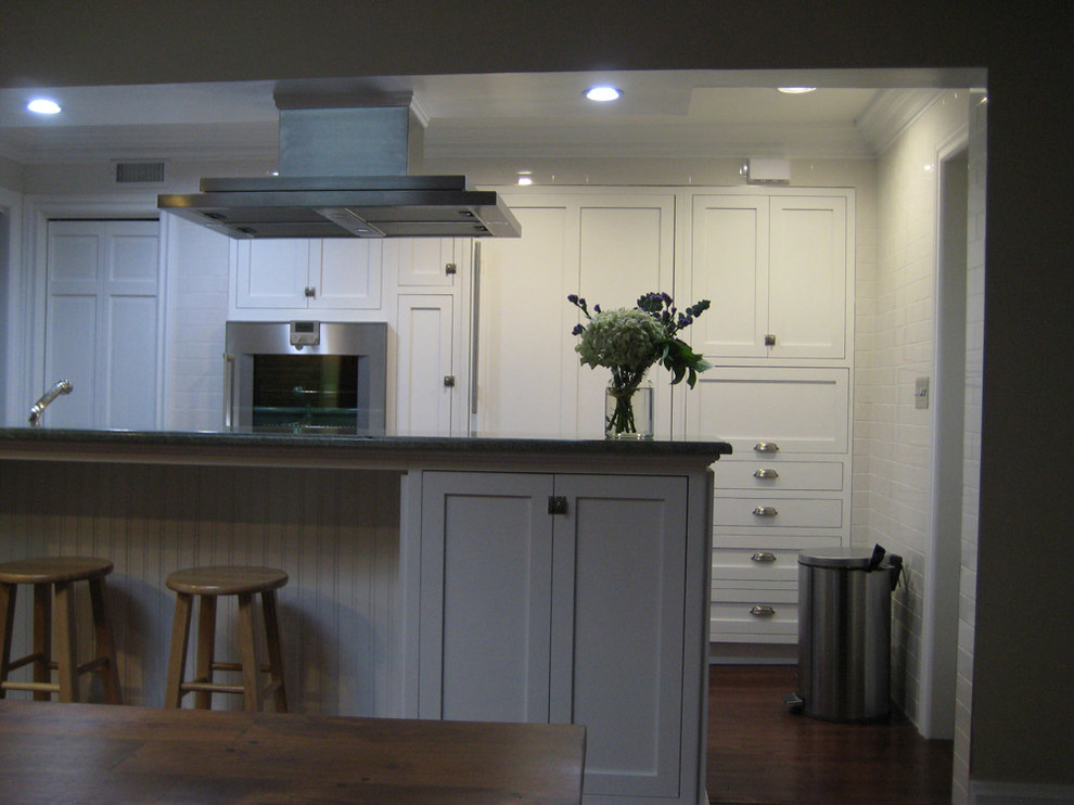 Inspiration for a mid-sized transitional galley dark wood floor eat-in kitchen remodel in New York with shaker cabinets, white cabinets, granite countertops, green backsplash, stone slab backsplash, stainless steel appliances, a farmhouse sink and a peninsula