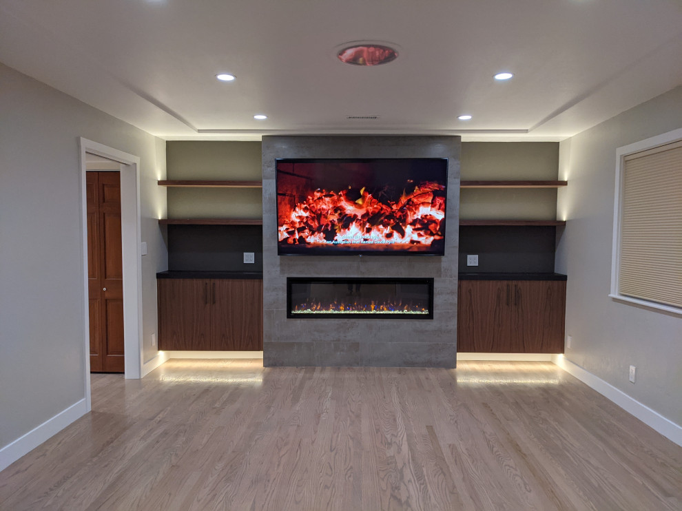 На фото: изолированная гостиная комната среднего размера в стиле ретро с коричневыми стенами, светлым паркетным полом, подвесным камином, фасадом камина из плитки, телевизором на стене и бежевым полом с