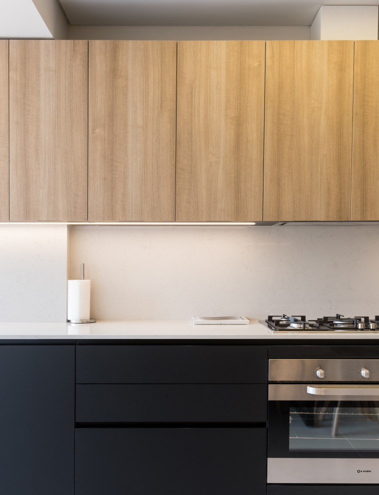 Foto på ett mellanstort funkis vit kök, med en integrerad diskho, svarta skåp, bänkskiva i kvarts, vitt stänkskydd, rostfria vitvaror och kalkstensgolv
