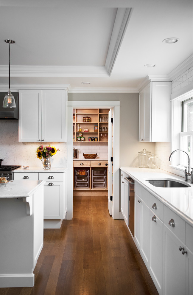 Inspiration for a large transitional u-shaped eat-in kitchen in New York with an undermount sink, shaker cabinets, white cabinets, quartz benchtops, white splashback, subway tile splashback, stainless steel appliances, dark hardwood floors, with island, brown floor and white benchtop.