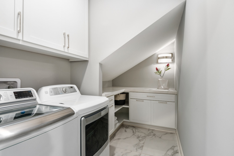 Small modern single-wall laundry cupboard in Columbus with shaker cabinets, white cabinets, engineered stone countertops, grey walls, porcelain flooring, a side by side washer and dryer, grey floors, white worktops and a vaulted ceiling.