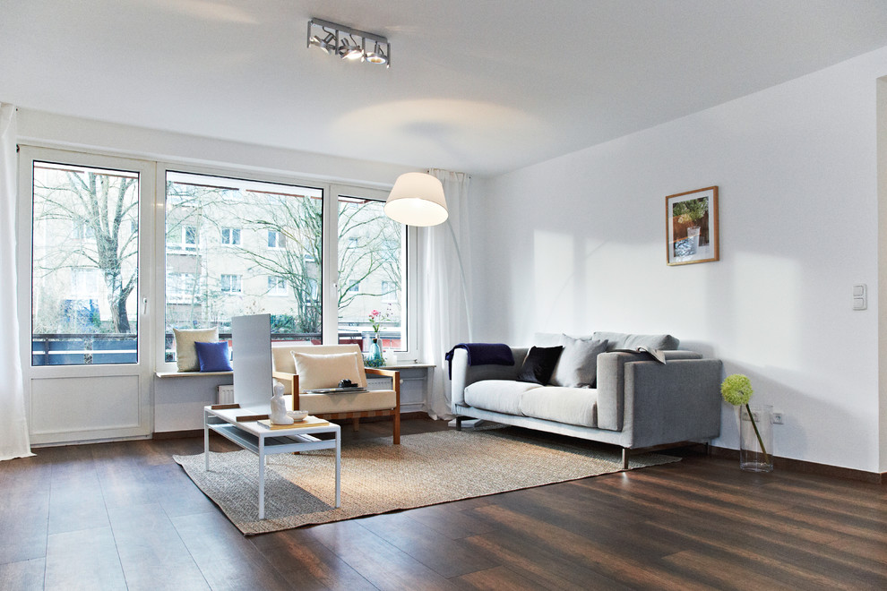 Mittelgroßes, Offenes Modernes Wohnzimmer ohne Kamin mit weißer Wandfarbe, dunklem Holzboden, freistehendem TV und braunem Boden in Nürnberg