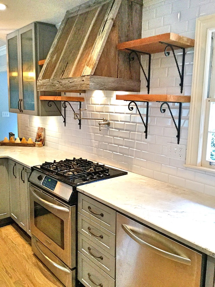 Example of a mid-sized mountain style u-shaped light wood floor open concept kitchen design in Atlanta with a farmhouse sink, shaker cabinets, gray cabinets, quartzite countertops, white backsplash, subway tile backsplash, stainless steel appliances and a peninsula