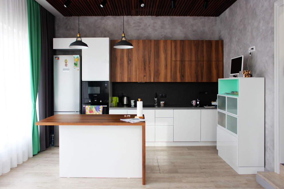 Photo of a mid-sized contemporary single-wall kitchen in Novosibirsk with an undermount sink, flat-panel cabinets, black splashback, black appliances, vinyl floors, with island, beige floor, white cabinets and grey benchtop.