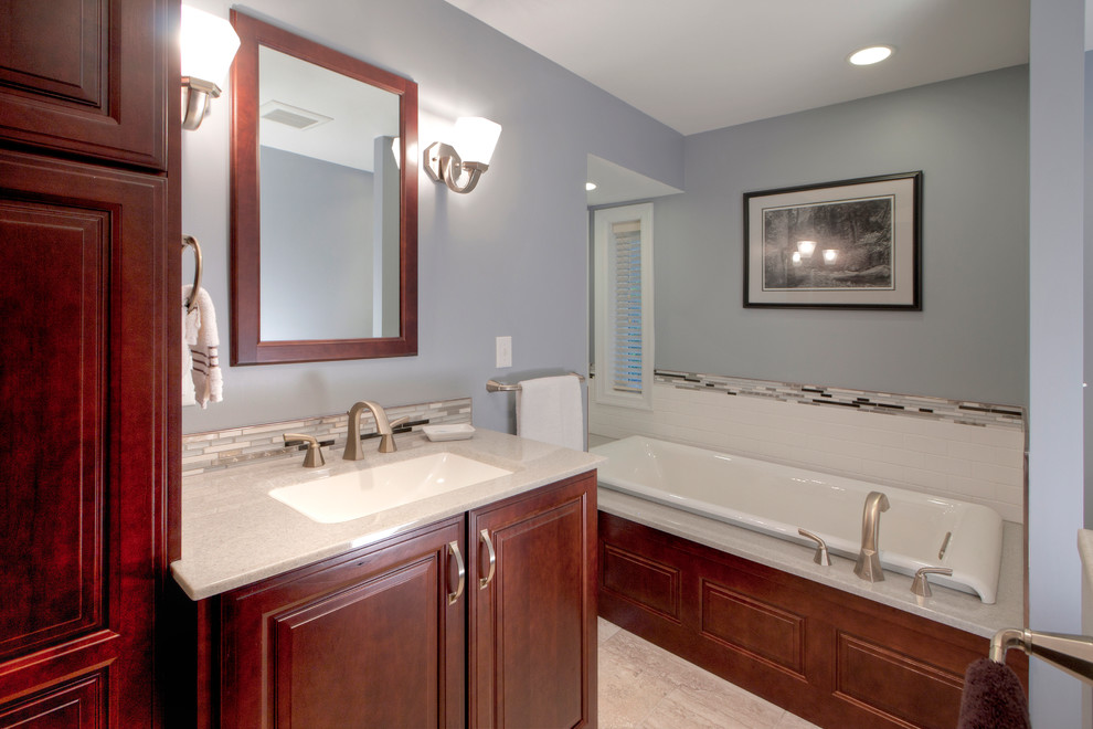 Photo of a large contemporary master bathroom in St Louis with an integrated sink, recessed-panel cabinets, medium wood cabinets, onyx benchtops, an alcove tub, a corner shower, a one-piece toilet, multi-coloured tile, glass tile, grey walls and ceramic floors.