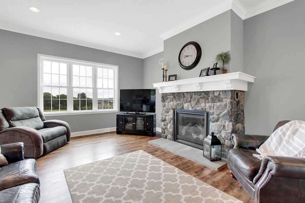 Inspiration for a large traditional open concept family room in Other with grey walls, vinyl floors, a standard fireplace, a stone fireplace surround, a corner tv and brown floor.