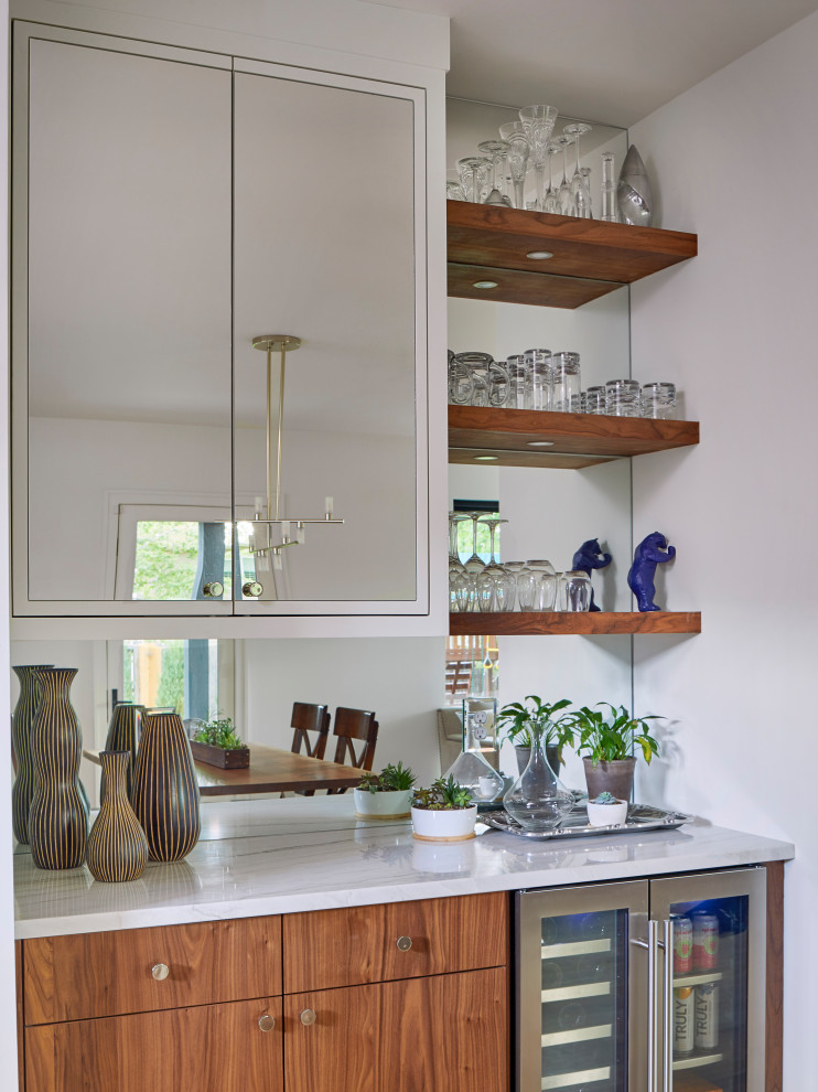 Photo of a large scandinavian u-shaped home bar in Denver with an undermount sink, flat-panel cabinets, medium wood cabinets, quartzite benchtops, white splashback, ceramic splashback, light hardwood floors and white benchtop.