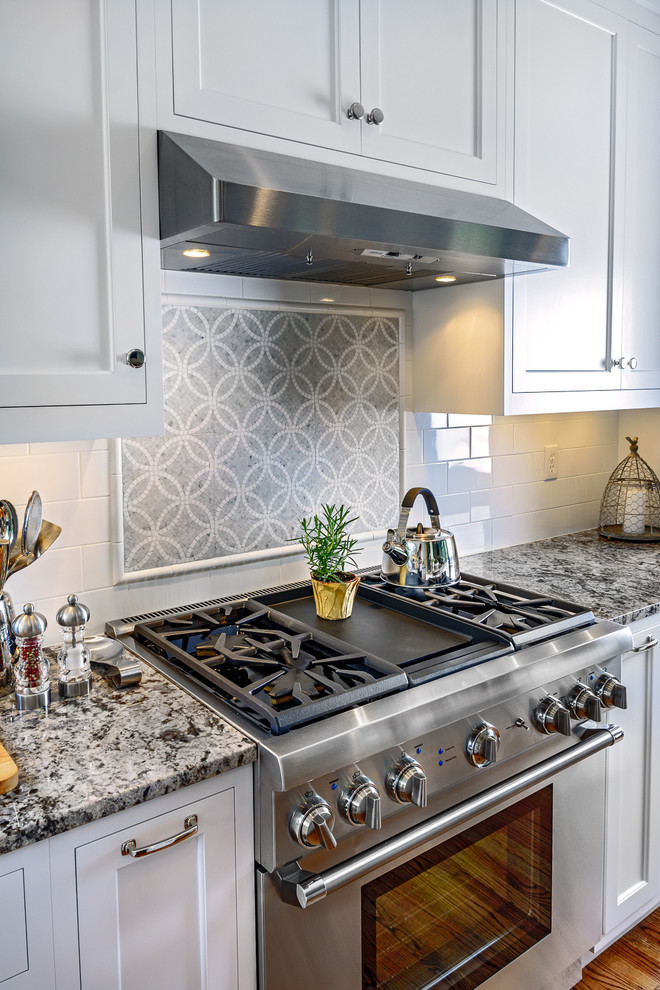 Inspiration for a mid-sized transitional l-shaped eat-in kitchen in St Louis with an undermount sink, beaded inset cabinets, white cabinets, granite benchtops, grey splashback, mosaic tile splashback, panelled appliances, medium hardwood floors and with island.