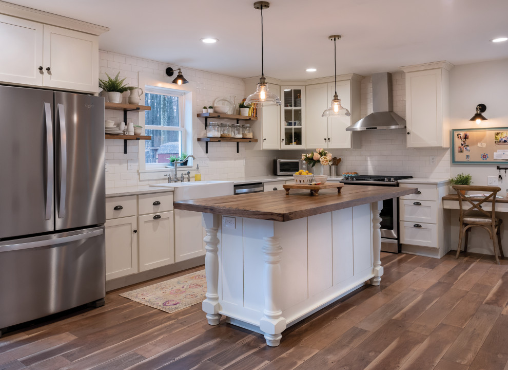 Kitchen - kitchen idea with a farmhouse sink, white cabinets, white backsplash, subway tile backsplash, stainless steel appliances and an island