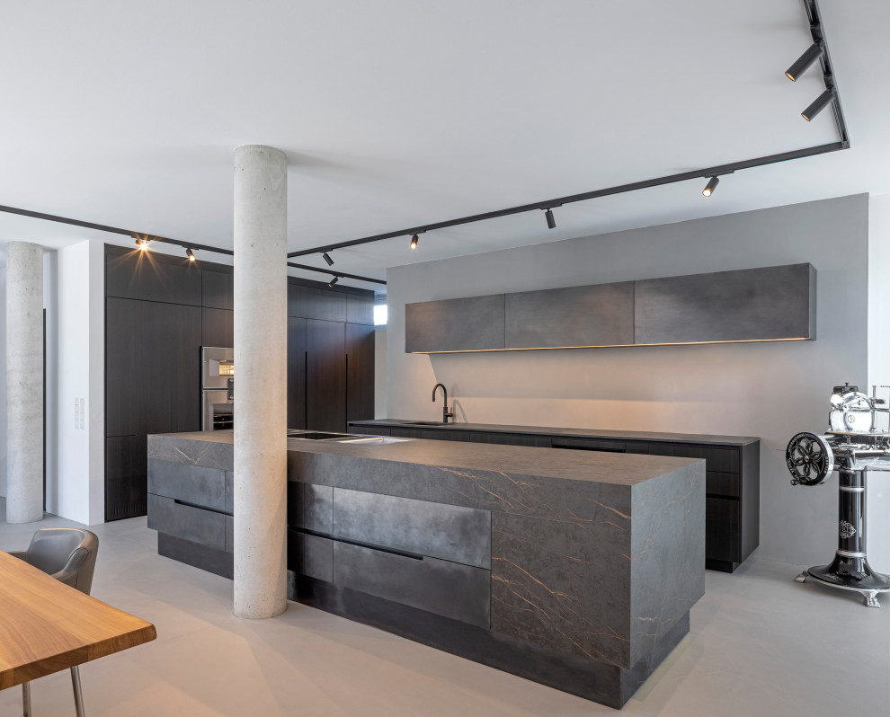 Esempio di una grande cucina minimalista con lavello integrato, ante lisce, ante nere, elettrodomestici in acciaio inossidabile, pavimento in cemento e top nero