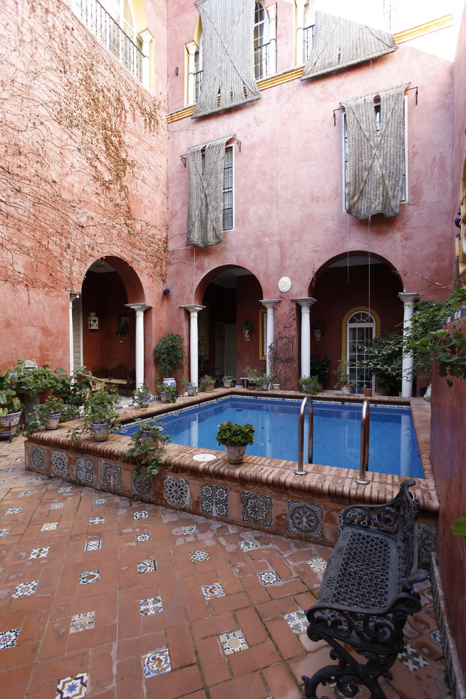 Photo of a mediterranean courtyard rectangular aboveground pool in Other with brick pavers.