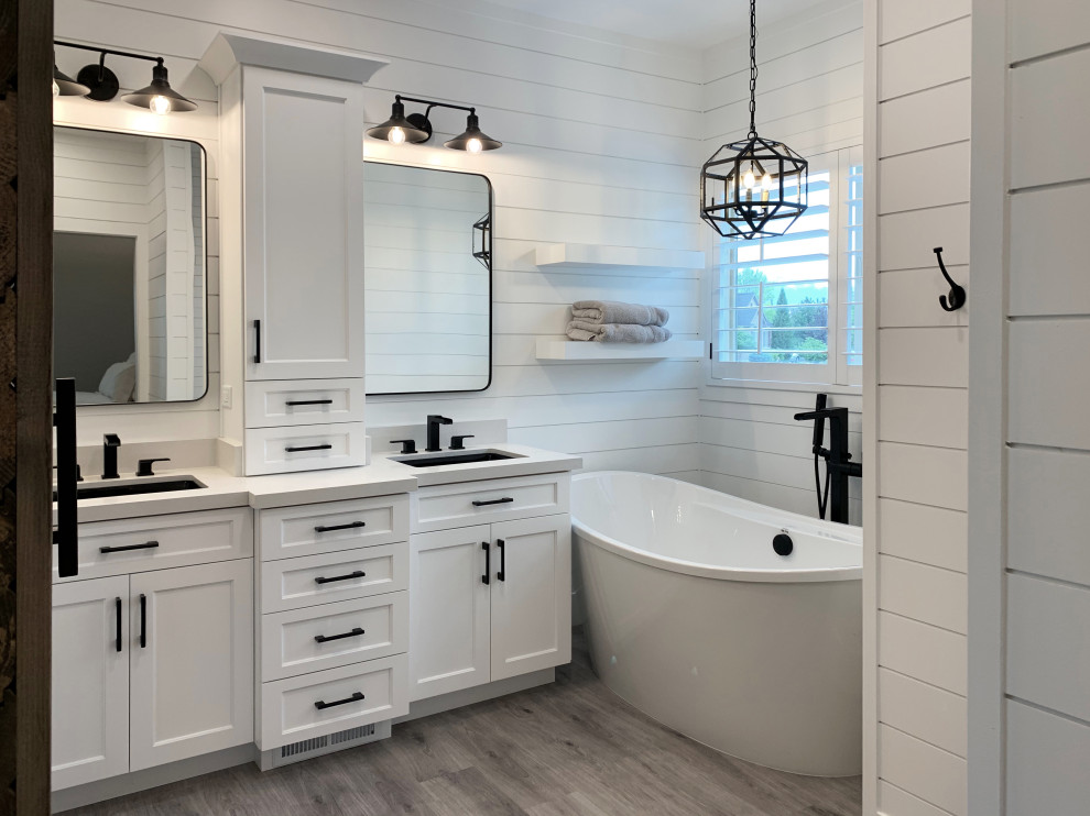 Photo of a large master bathroom in Salt Lake City with shaker cabinets, white cabinets, a freestanding tub, a corner shower, white tile, subway tile, white walls, light hardwood floors, an undermount sink, engineered quartz benchtops, an open shower, white benchtops, a shower seat, a double vanity, a built-in vanity and planked wall panelling.