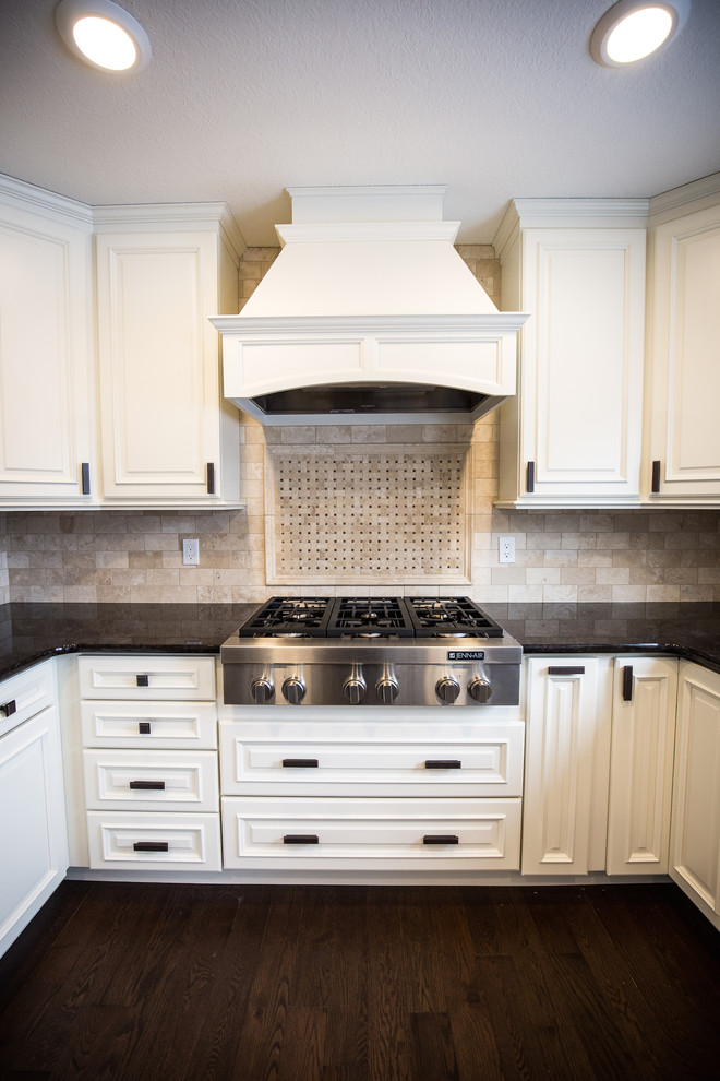 Inspiration for a mid-sized timeless u-shaped dark wood floor eat-in kitchen remodel in Edmonton with a drop-in sink, white cabinets, granite countertops, beige backsplash, stone tile backsplash, stainless steel appliances and an island