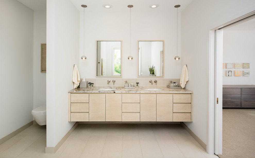 Photo of a large scandinavian master bathroom in Minneapolis with an undermount sink, flat-panel cabinets, light wood cabinets, marble benchtops, a wall-mount toilet, beige tile, porcelain tile, white walls and porcelain floors.
