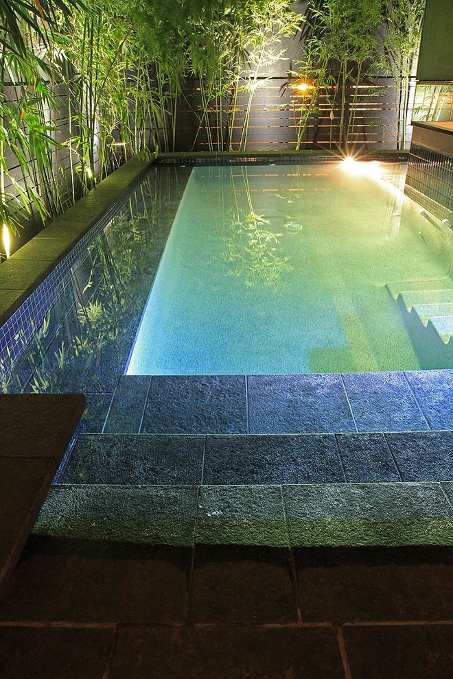 Small eclectic backyard l-shaped pool in Brisbane with natural stone pavers.