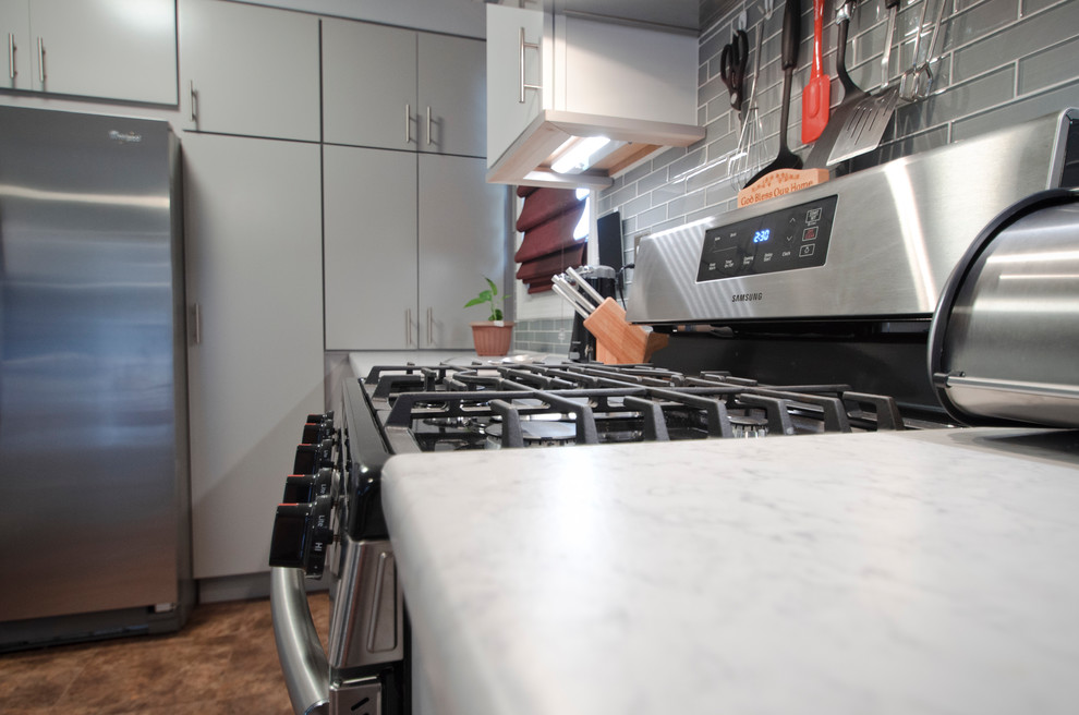 Eat-in kitchen - small modern galley vinyl floor and brown floor eat-in kitchen idea in Chicago with an integrated sink, flat-panel cabinets, gray cabinets, laminate countertops, gray backsplash, glass tile backsplash, stainless steel appliances and no island