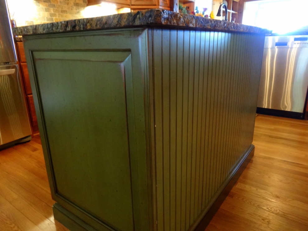 Inspiration for a mid-sized rustic l-shaped medium tone wood floor eat-in kitchen remodel in Charlotte with a farmhouse sink, raised-panel cabinets, dark wood cabinets, granite countertops, multicolored backsplash, stone tile backsplash, stainless steel appliances and an island