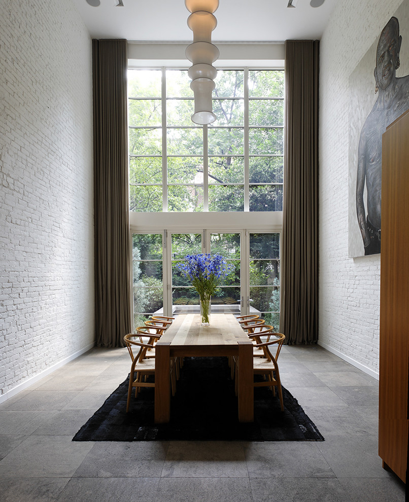 Contemporary dining room in New York with white walls and slate floors.