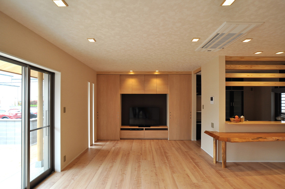 Photo of a large asian open concept living room in Other with white walls, plywood floors, a freestanding tv and brown floor.