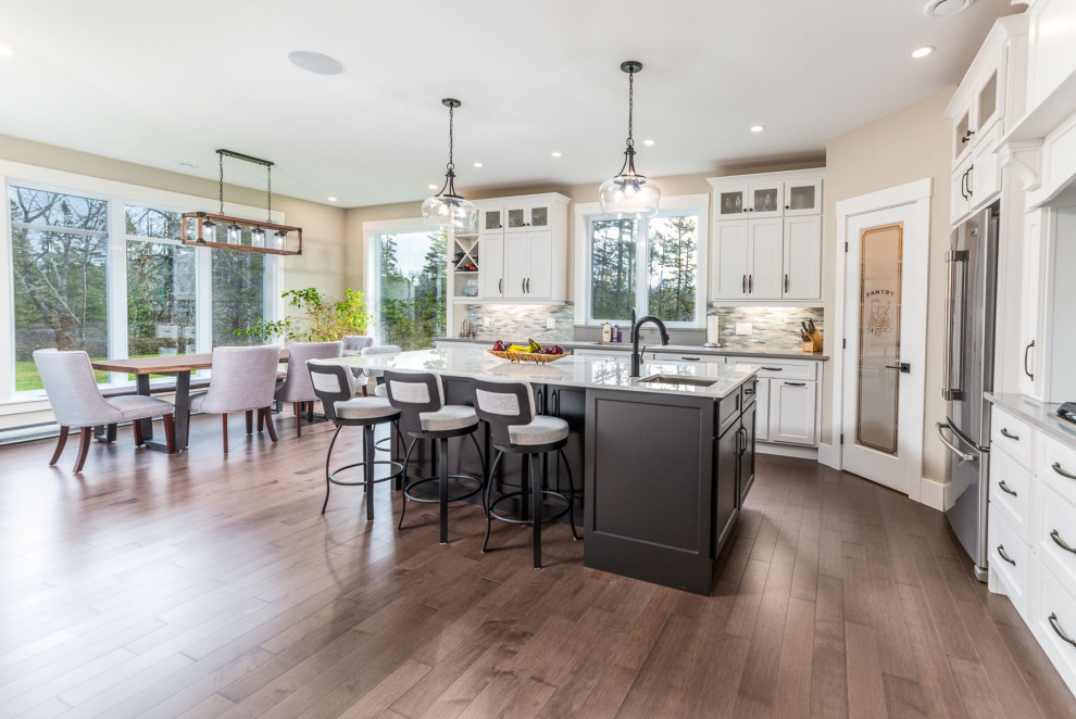 Inspiration for a mid-sized transitional medium tone wood floor and brown floor open concept kitchen remodel with an undermount sink, shaker cabinets, white cabinets, granite countertops, gray backsplash, mosaic tile backsplash, stainless steel appliances, an island and gray countertops