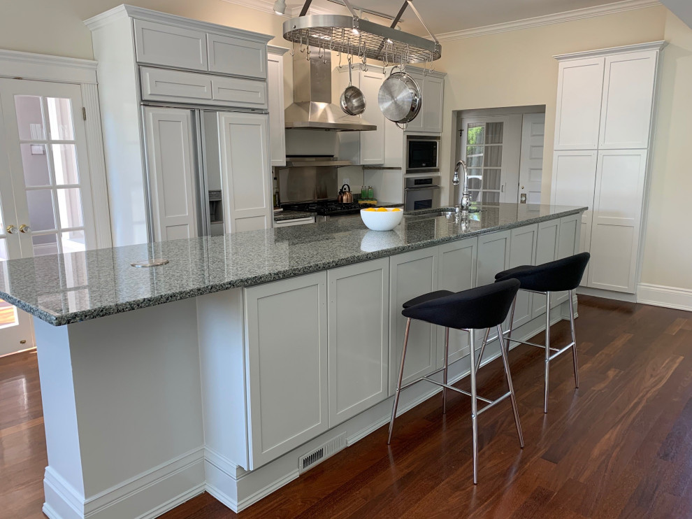 Example of a large transitional single-wall dark wood floor and brown floor enclosed kitchen design in Seattle with an undermount sink, shaker cabinets, white cabinets, granite countertops, gray backsplash, metal backsplash, stainless steel appliances, an island and gray countertops
