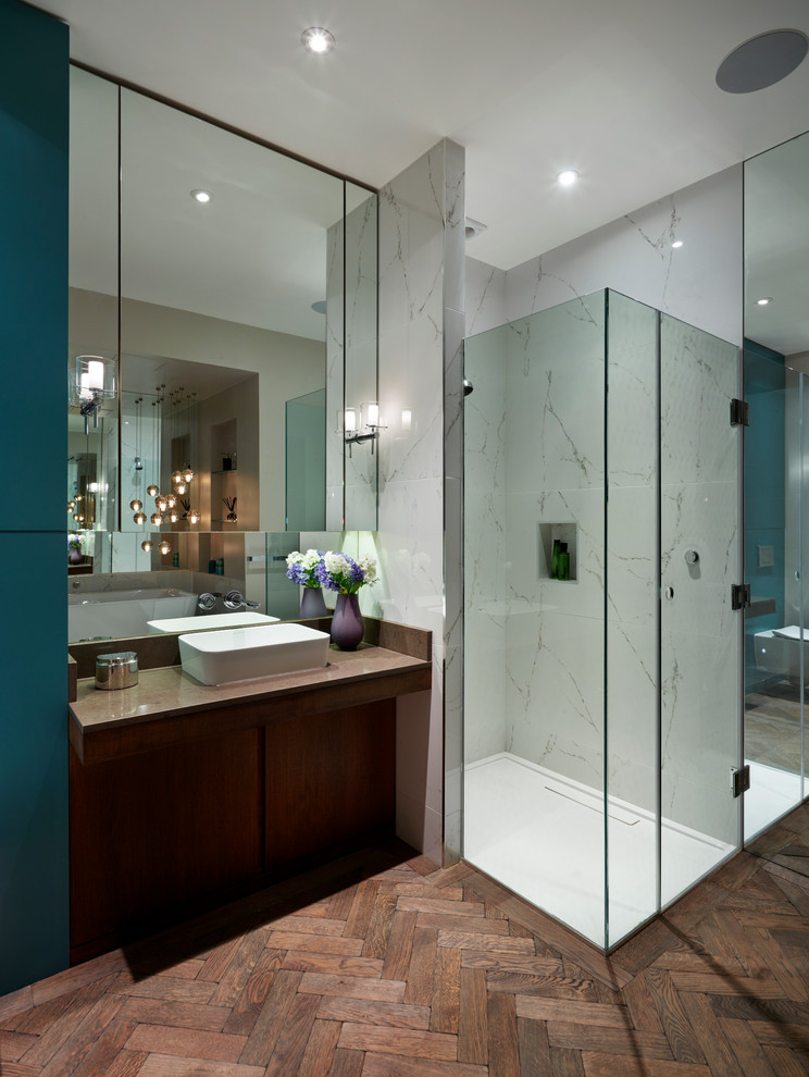 Design ideas for a contemporary master bathroom in London with flat-panel cabinets, dark wood cabinets, solid surface benchtops, a freestanding tub, an open shower, a wall-mount toilet, porcelain tile, dark hardwood floors, a vessel sink and a hinged shower door.