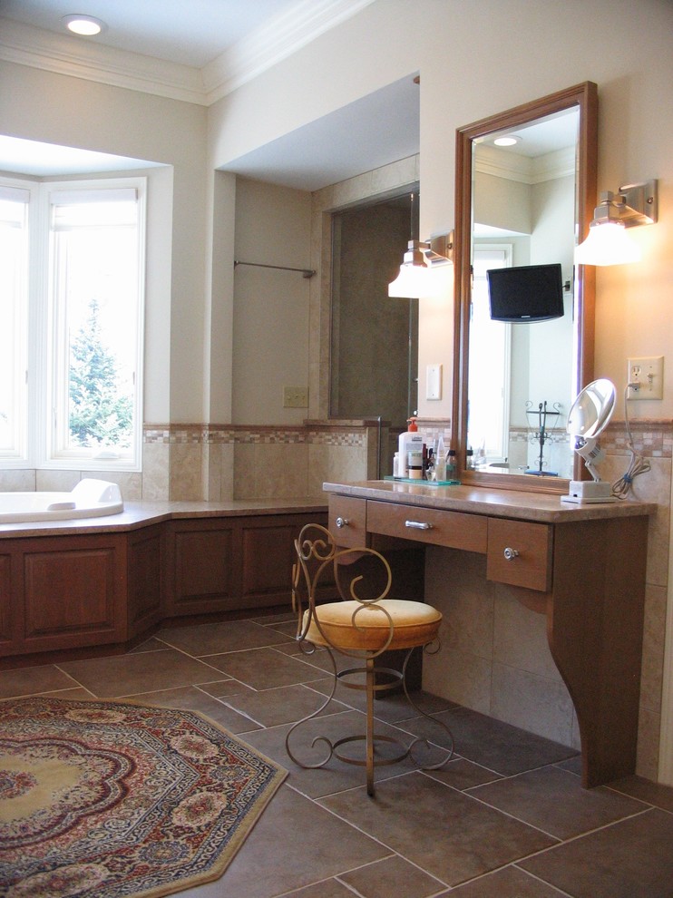 Photo of a mid-sized traditional master bathroom in Minneapolis with an undermount sink, raised-panel cabinets, medium wood cabinets, a drop-in tub, a double shower, a two-piece toilet, brown tile, stone tile, beige walls and travertine floors.