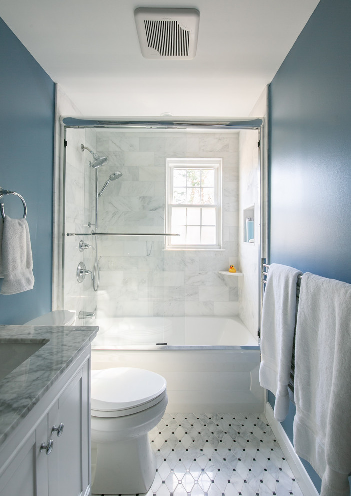 Klassisk inredning av ett litet grå grått en-suite badrum, med skåp i shakerstil, vita skåp, ett badkar i en alkov, en dusch/badkar-kombination, en toalettstol med separat cisternkåpa, blå kakel, marmorkakel, blå väggar, marmorgolv, ett undermonterad handfat, marmorbänkskiva, grått golv och dusch med skjutdörr