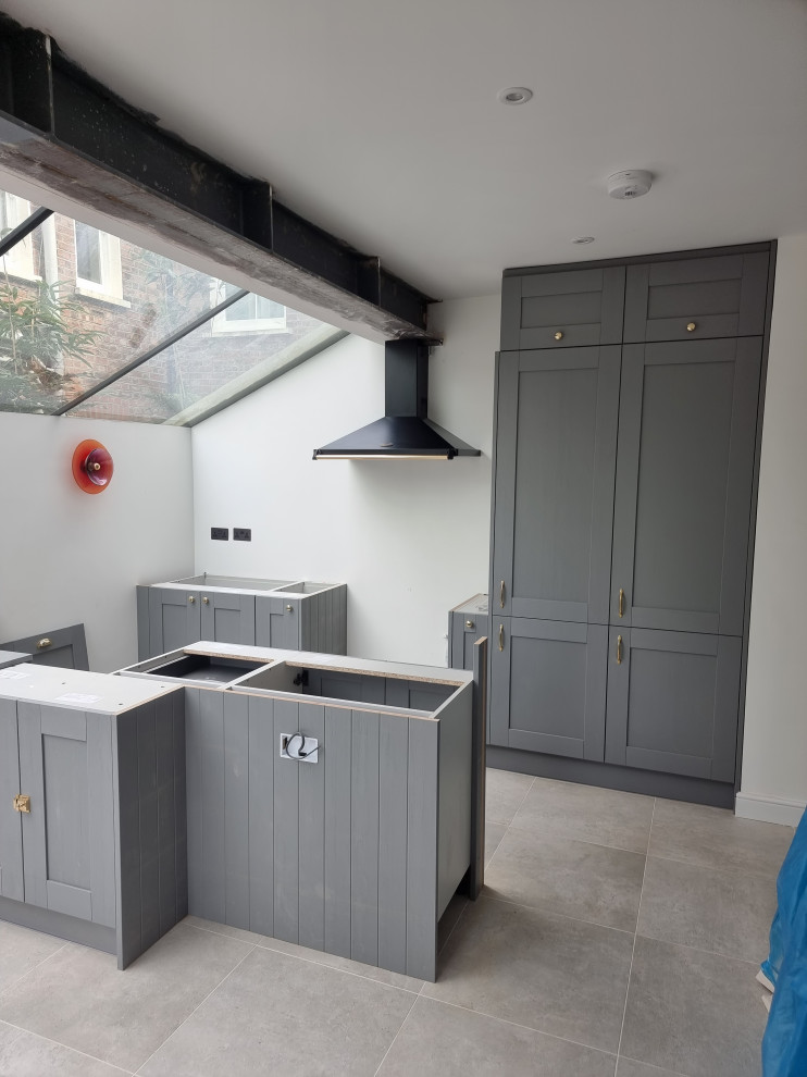 Design ideas for a large traditional single-wall kitchen in London with a belfast sink, shaker cabinets, grey cabinets, quartz worktops, integrated appliances, porcelain flooring, an island and white worktops.