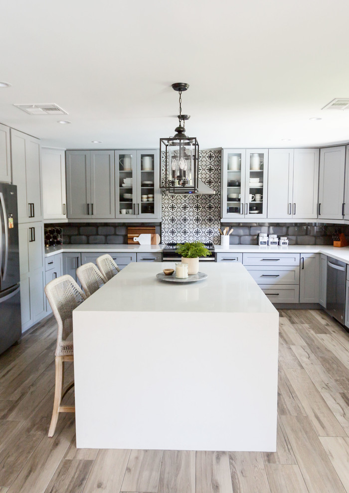 Inspiration for a mid-sized transitional u-shaped light wood floor and gray floor eat-in kitchen remodel in Phoenix with an undermount sink, recessed-panel cabinets, gray cabinets, quartz countertops, multicolored backsplash, ceramic backsplash, stainless steel appliances, an island and white countertops