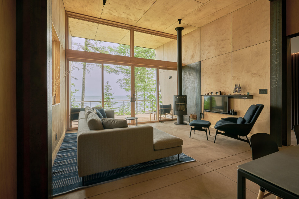 На фото: открытая гостиная комната в стиле рустика с бетонным полом, печью-буржуйкой, фасадом камина из металла, телевизором на стене, деревянным потолком и деревянными стенами с